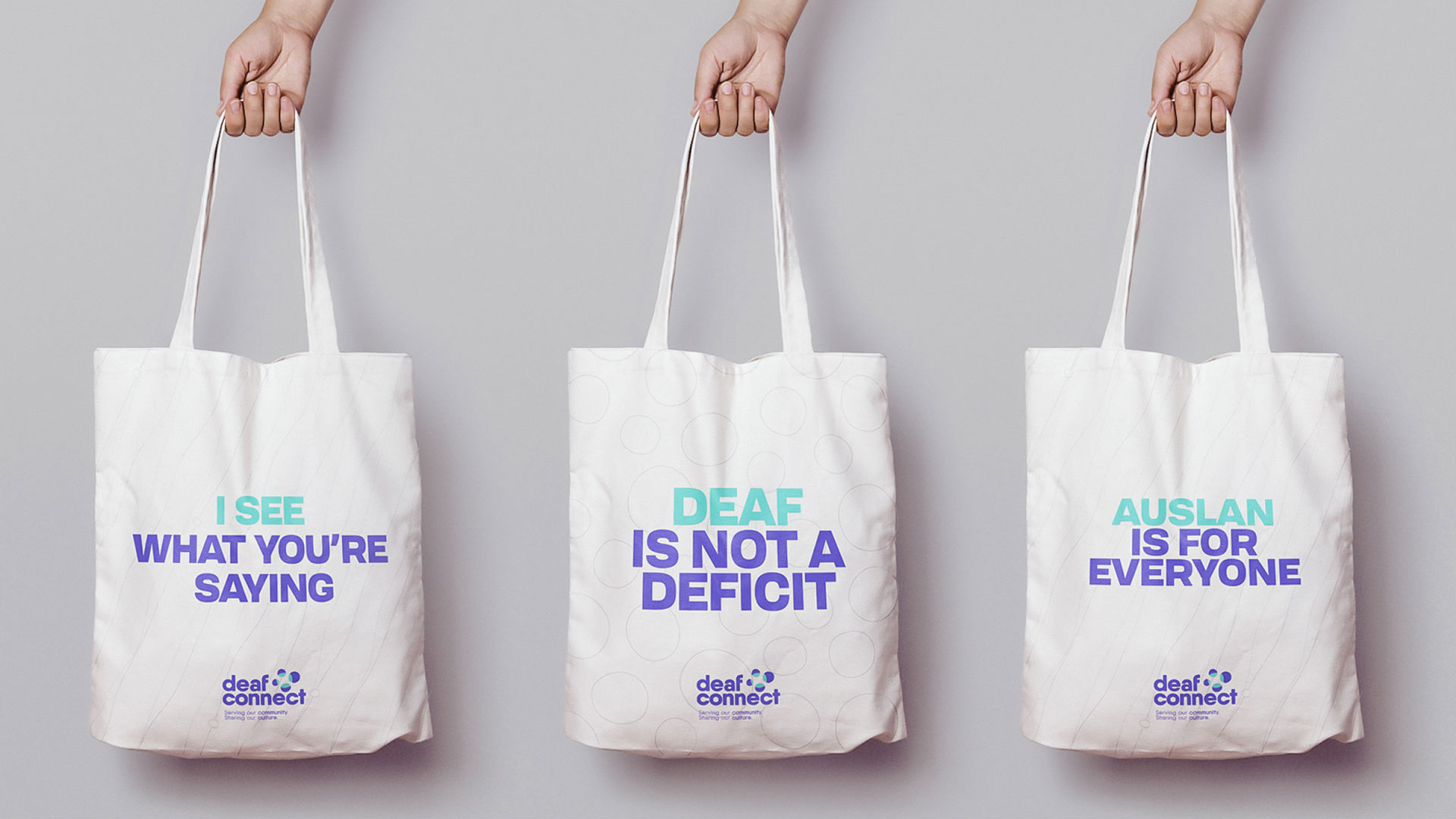 Three tote bags that say "I see what you're saying", "Deaf is not a deficit" "Auslan is for everyone"
